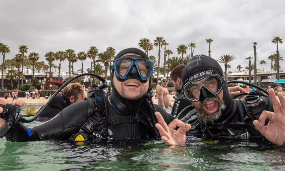 dwóch nurków w wodzie na tle plaży playa flamingo przy bazie bonito diving